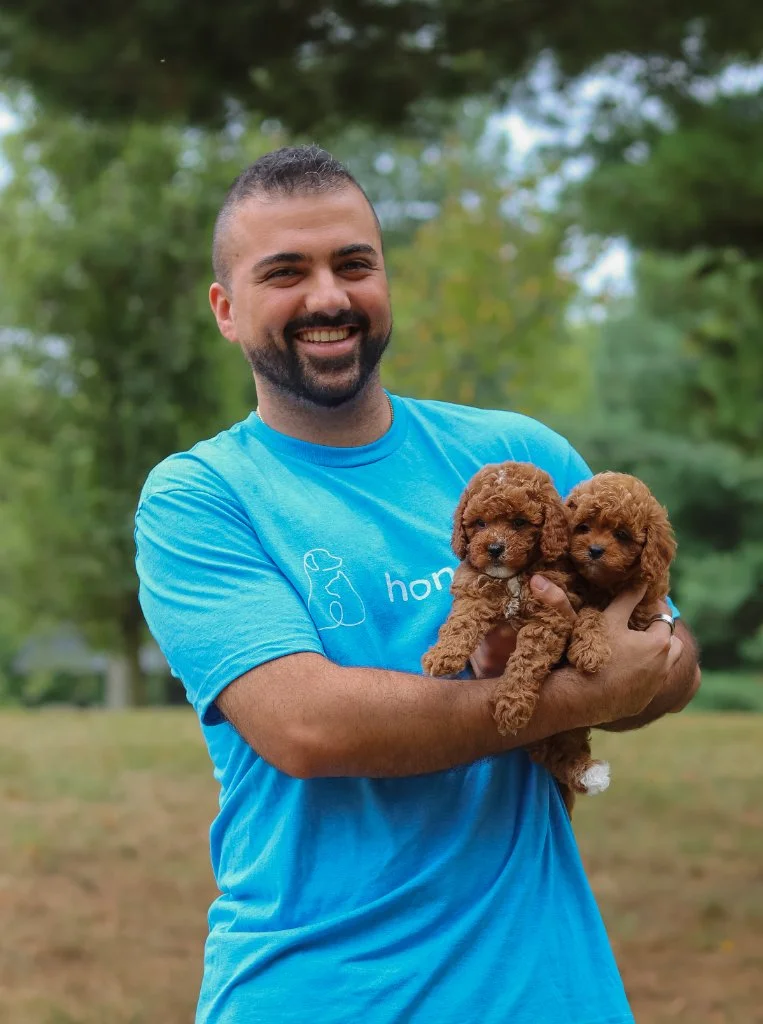 Man smiling holding two brown puppies